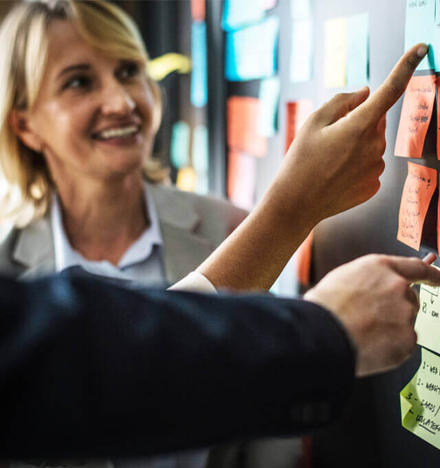 A team discuss the priority of user stories on post-its stuck to a wall.