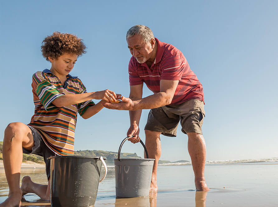 Father and son taking time gathering shellfish on the beach, after Dad has used "Check what you might get" to make sure his family are getting all the support they're entitled to.